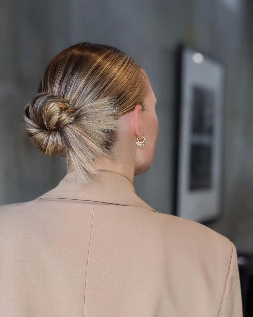 back view of a sleek spiky low bun summer hairstyle with a tan blazer