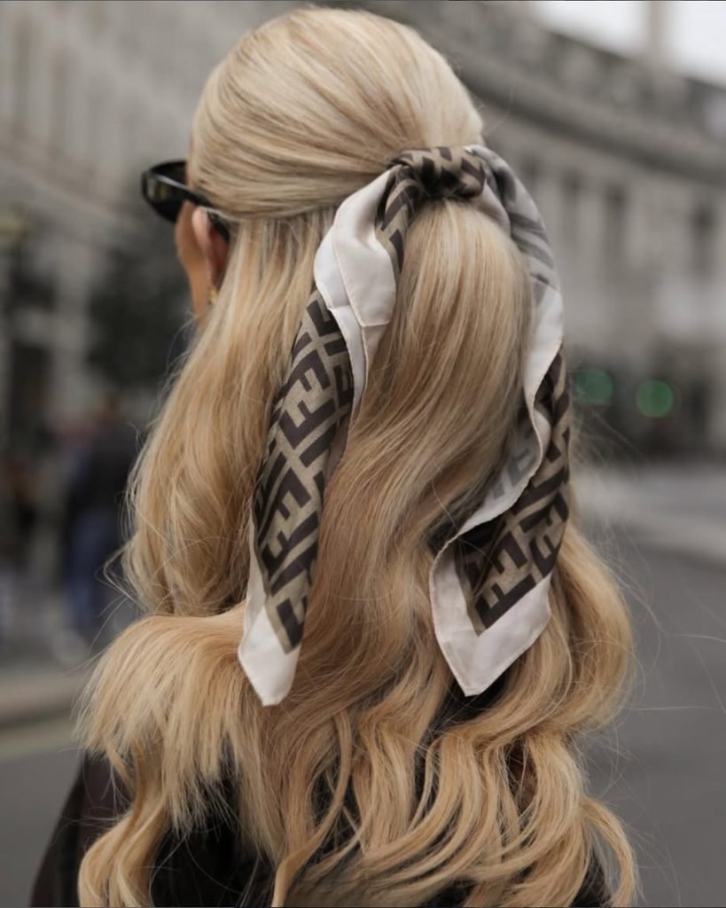 blonde woman wearing a geometric pattern silk scarf ponytail summer hairstyle