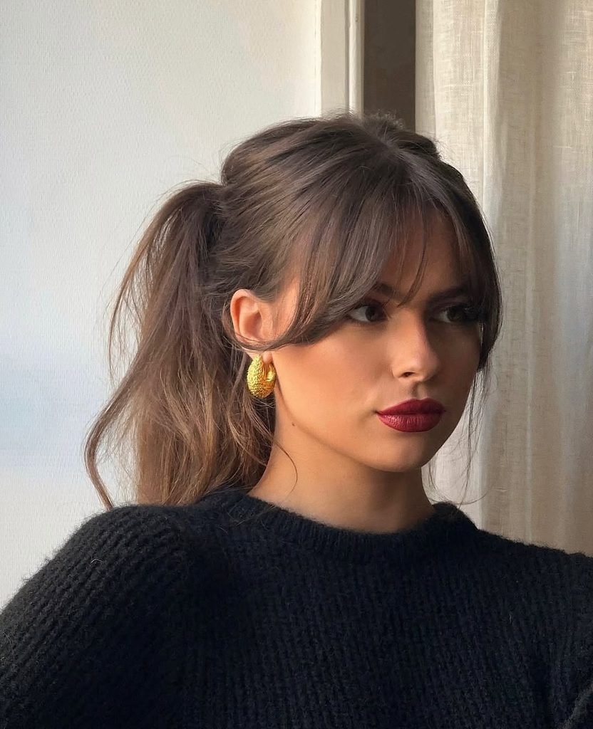 woman with curtain bangs and a high ponytail summer hairstyle