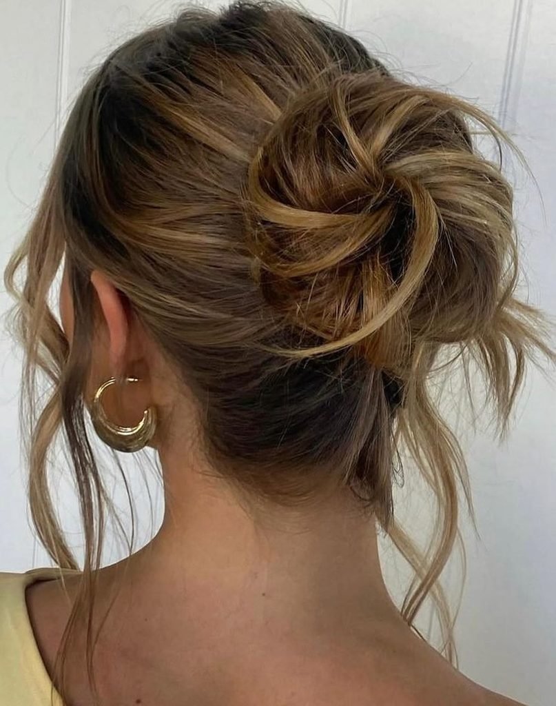 back view of a messy textured bun summer hairstyle with gold hoop earrings
