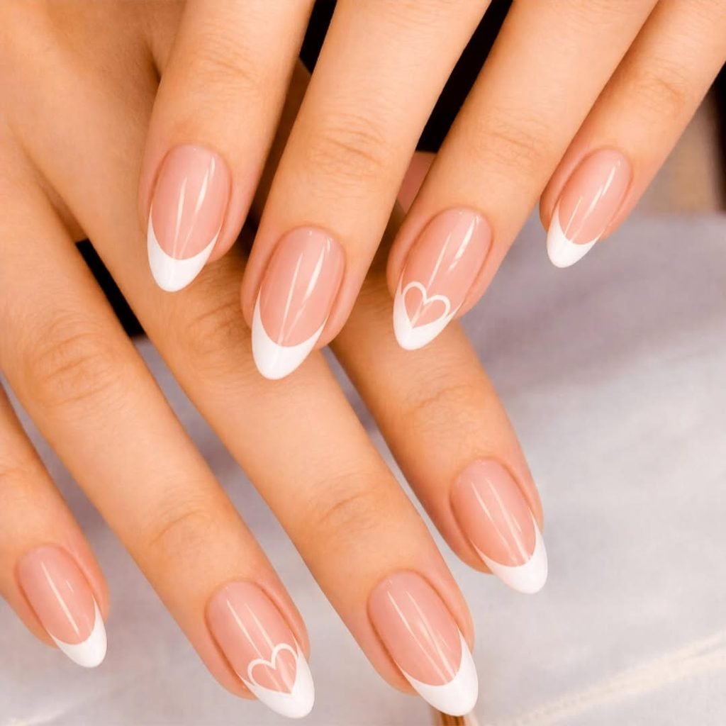 classic white french tip manicure on oval nails with a delicate heart accent design