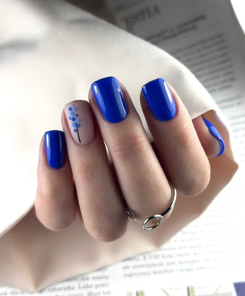 cobalt blue nails manicure with a nude accent nail featuring delicate blue floral art