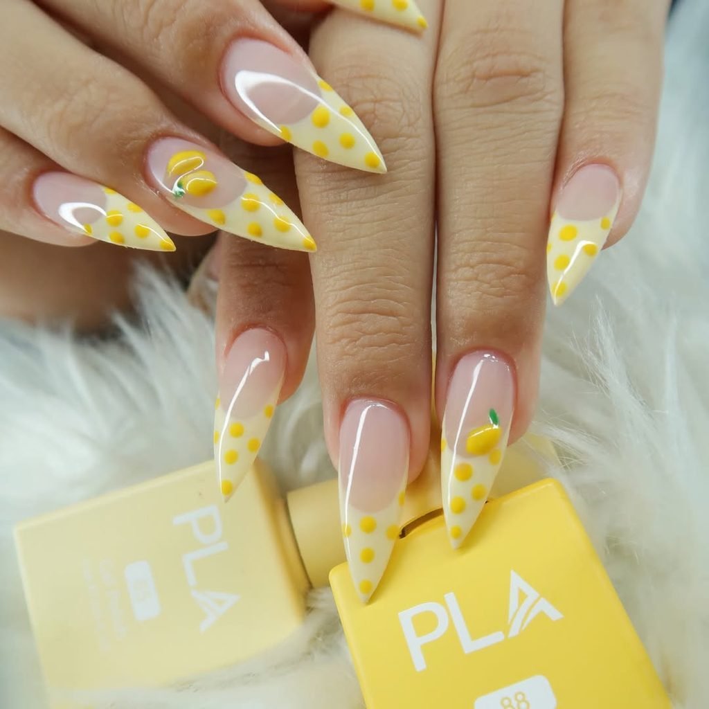 stiletto nails featuring yellow polka dot french tips and tiny lemon nail art