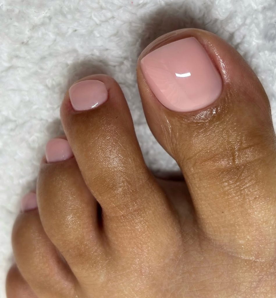 glossy light pastel pink polish applied neatly on a set of summer toe nails