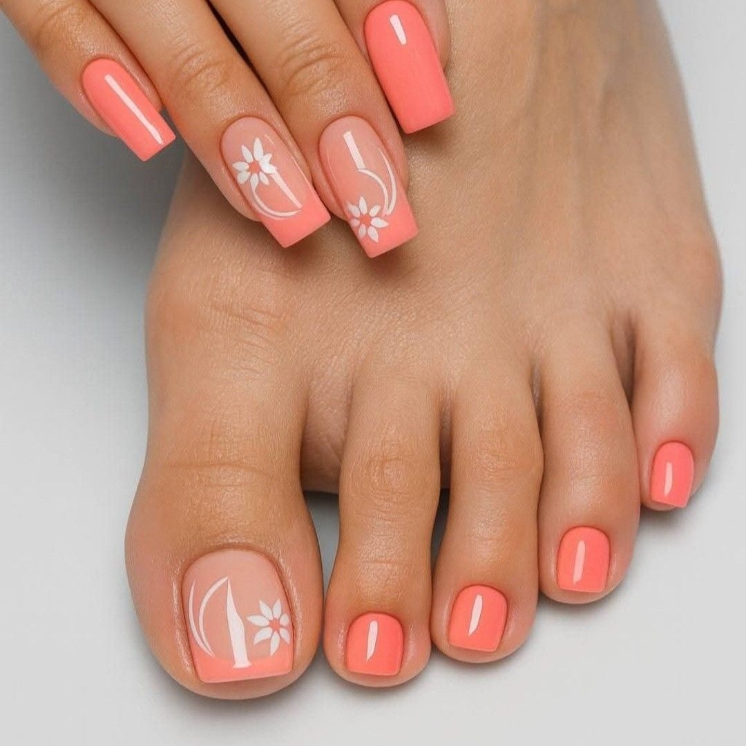 matching coral manicure and pedicure with white floral nail art on the accent nails