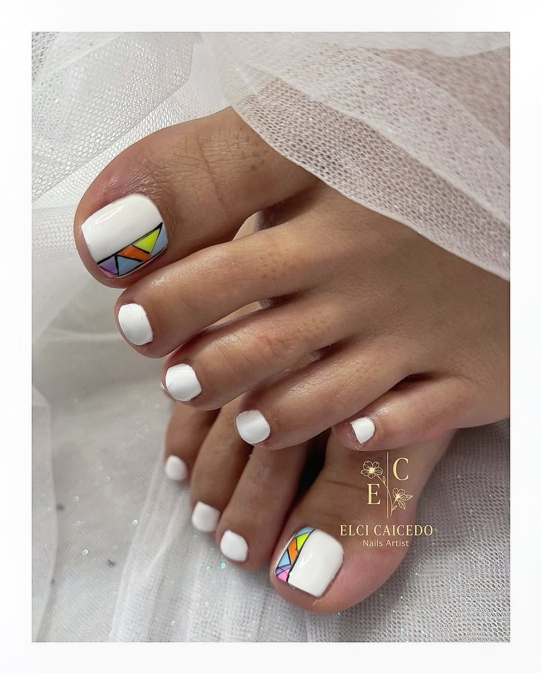 classic white pedicure featuring a colorful geometric mosaic pattern on the big toenails