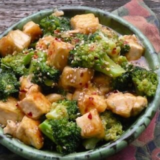 stir fried tofu and broccoli with sesame seeds and chili flakes in a bowl