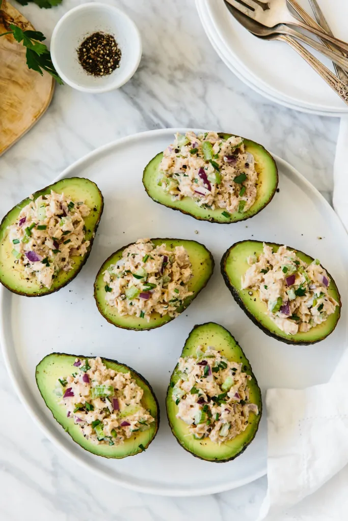 avocado halves stuffed with savory tuna salad on a white serving plate