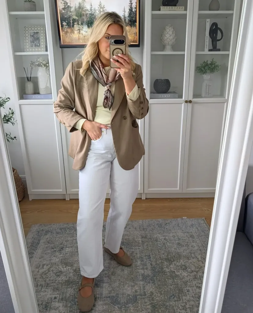 woman wearing a brown blazer, scarf, and wide leg white jeans