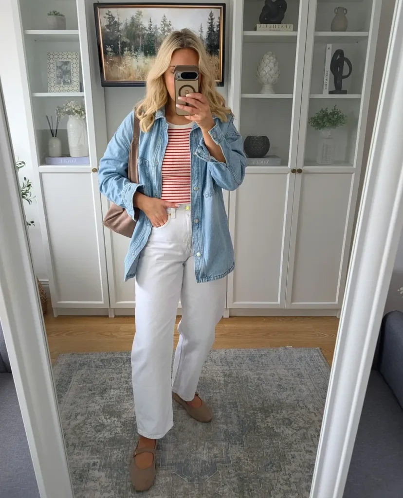 woman in a denim shirt, striped top, and wide leg white jeans