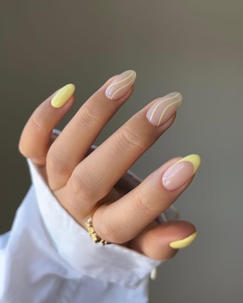 glossy almond nails with mixed light yellow french tips and wavy line art