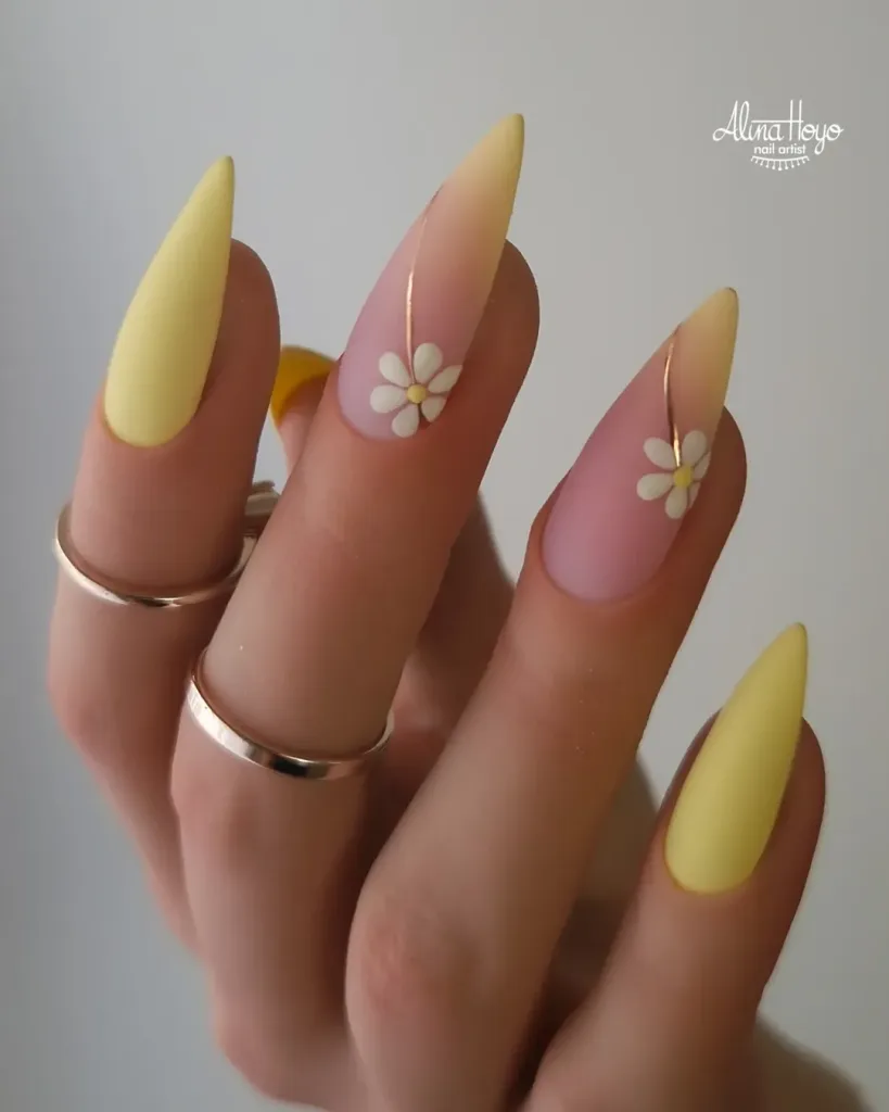 long stiletto nails with matte yellow tips and delicate white daisy flowers