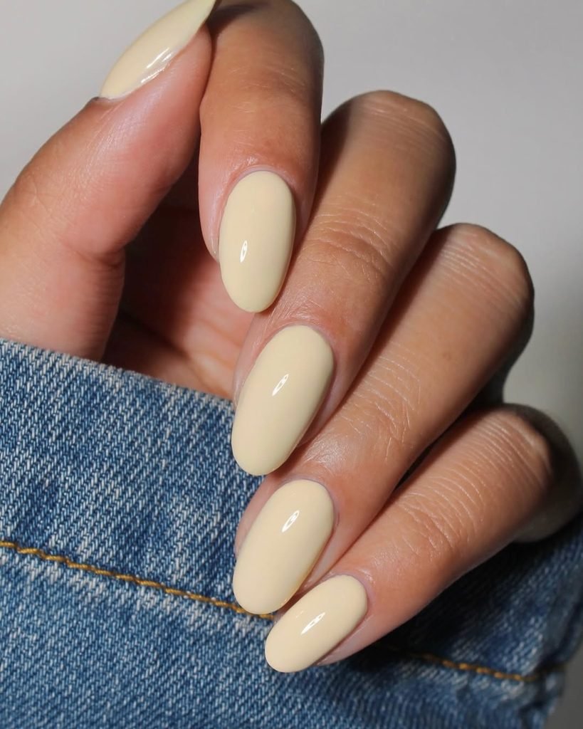 glossy oval shaped nails painted in a solid pale pastel yellow color