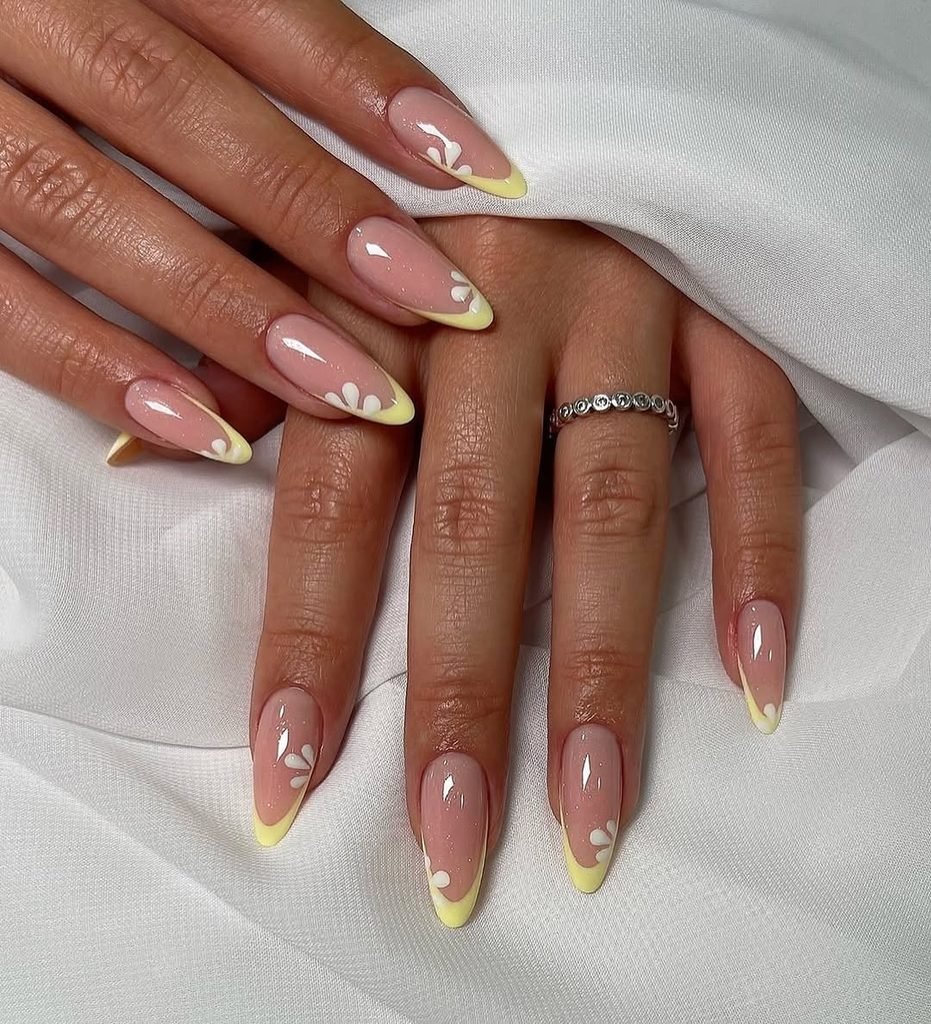 almond shaped nails with a glossy nude base and pastel yellow french tips