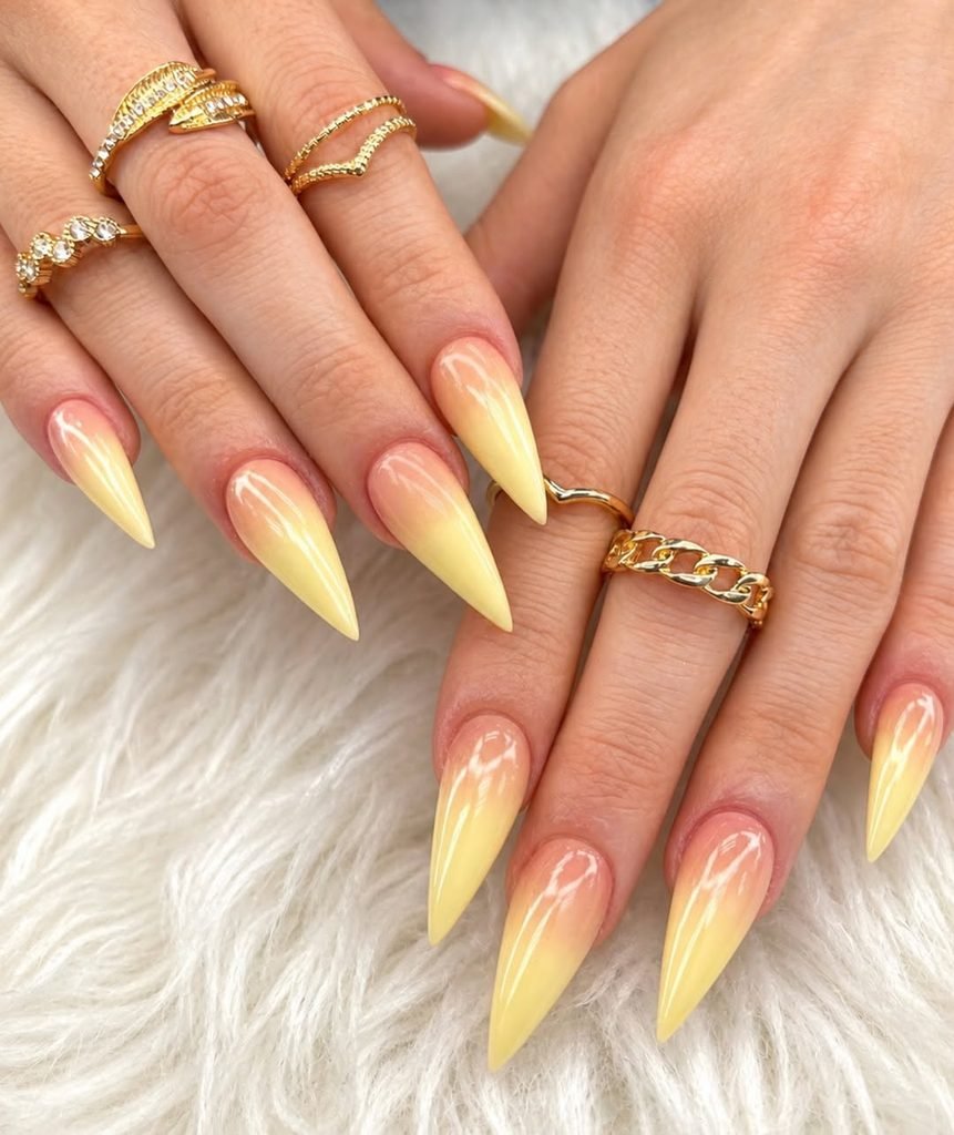 stiletto shaped nails featuring a soft orange to pastel yellow ombre gradient design