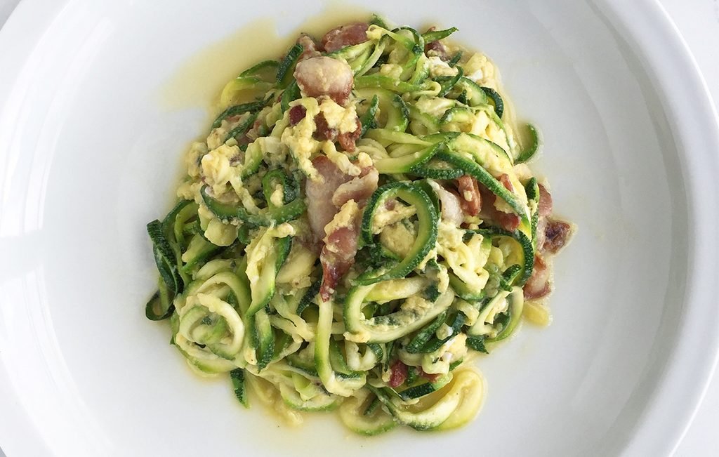 zucchini noodles carbonara with pancetta and creamy egg sauce on a plate