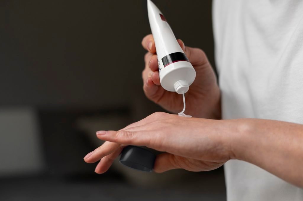 close up of woman squeezing white cream from a tube onto her hand