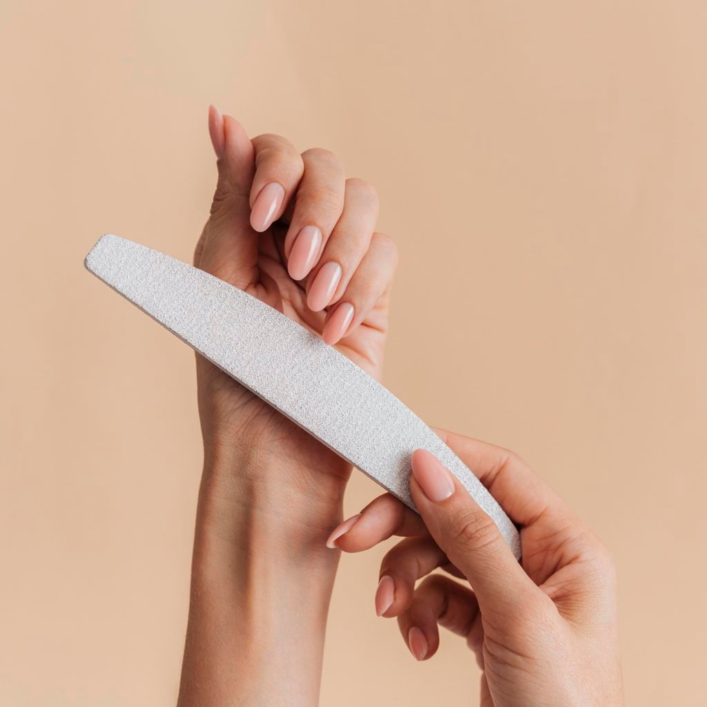 close up of woman's hands filing her own natural fingernails