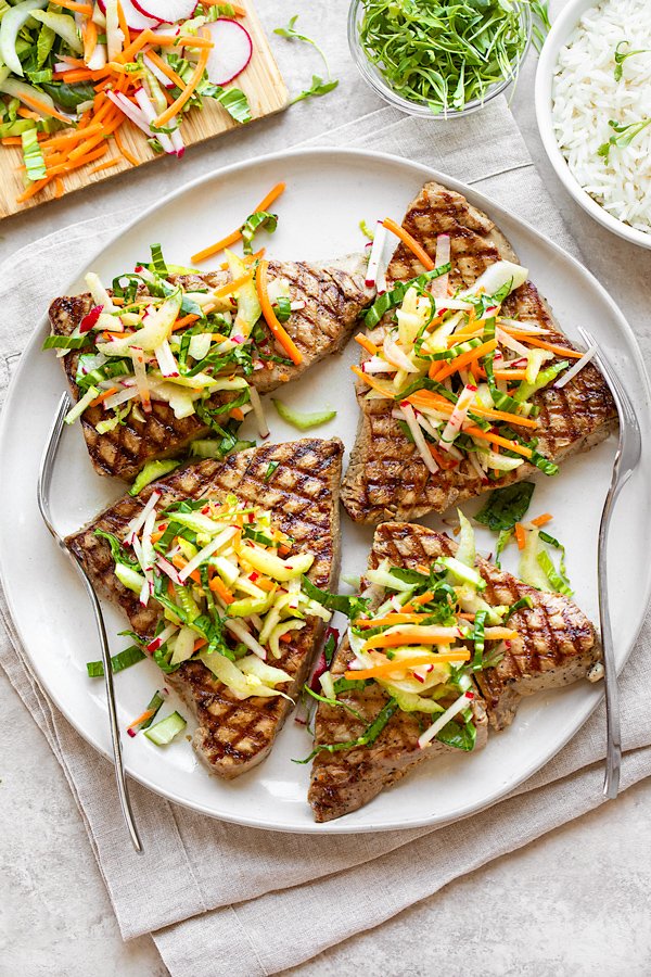 grilled tuna steaks topped with crunchy bok choy slaw on a white plate
