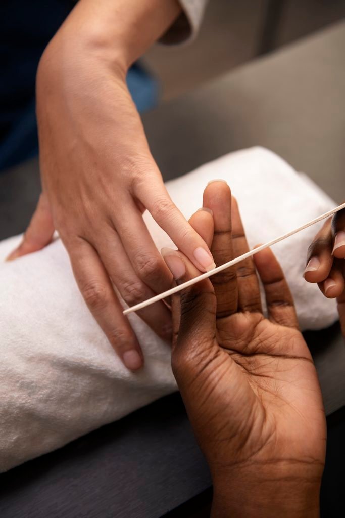 close up of dark skin hand filing nails during manicure