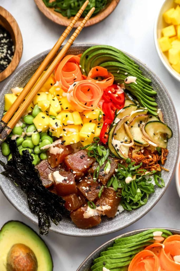 a tuna poke bowl filled with cubed fish, edamame, mango, avocado, and carrots