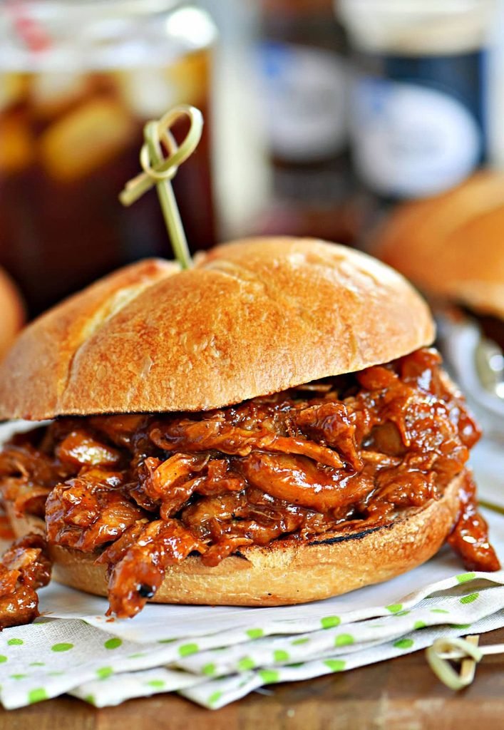 a pulled chicken sandwich dripping with barbecue sauce on a toasted brioche bun