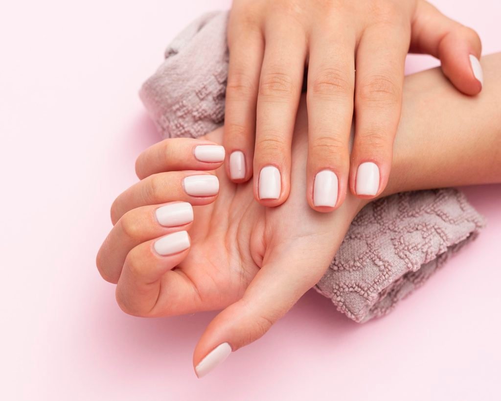 woman showing her hands with light pink manicured nails and lavender towel