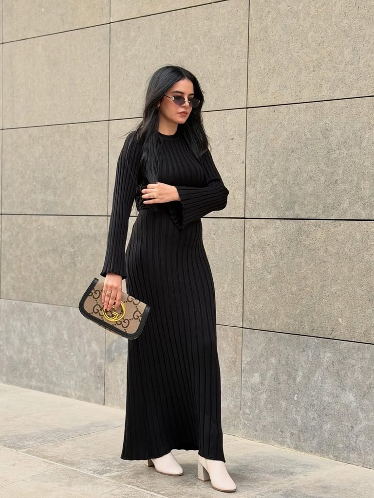 woman in black ribbed long sleeve maxi dress holding printed clutch