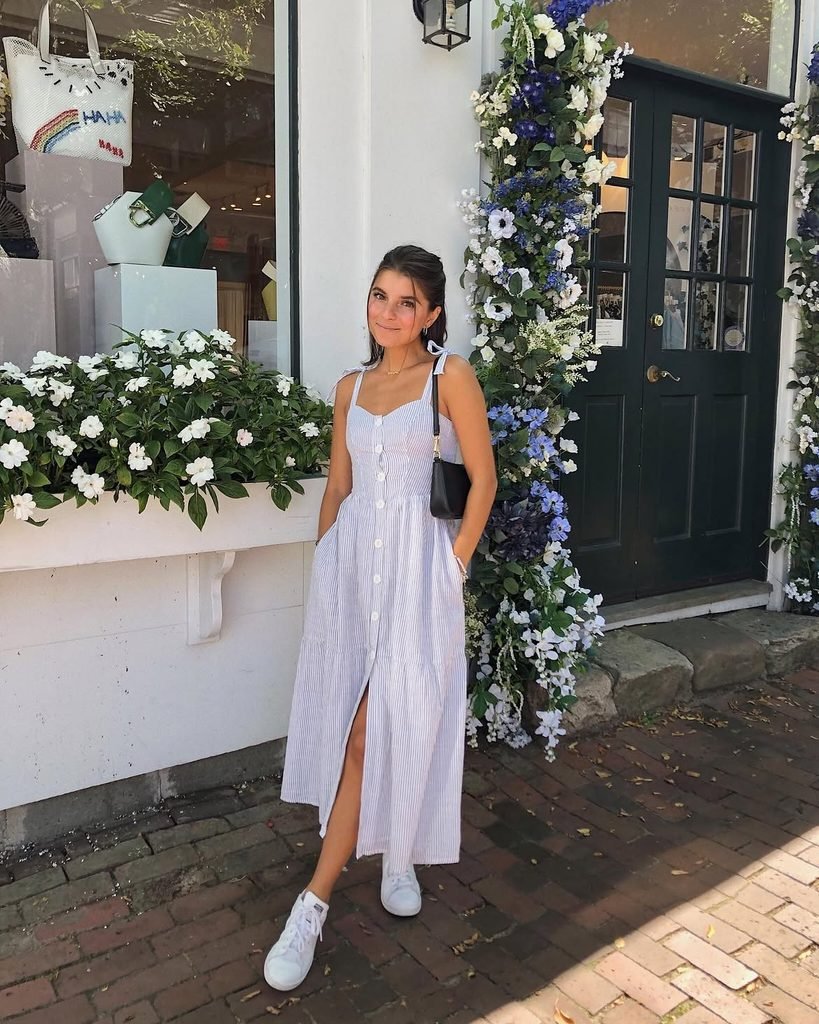 woman in blue striped midi dress standing outside shop with flowers