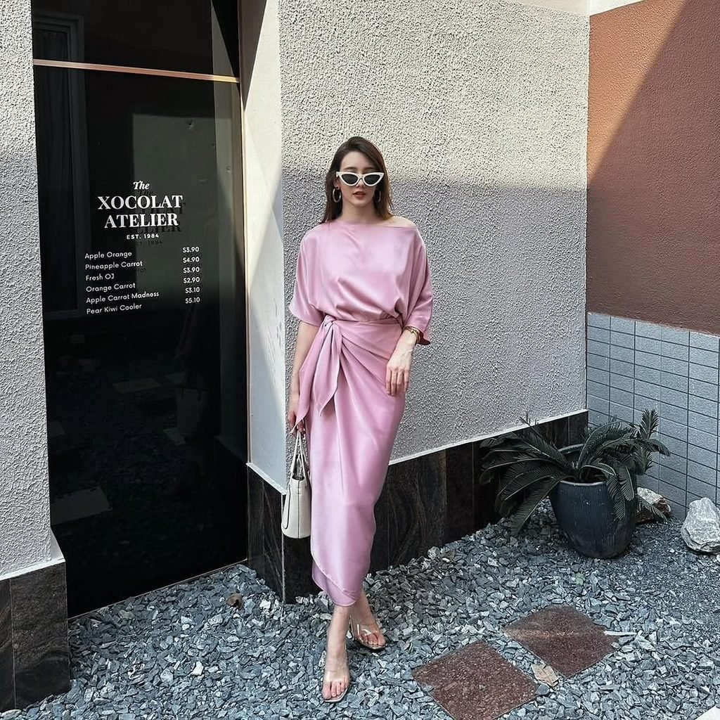 woman in pink satin wrap dress and sunglasses posing near storefront