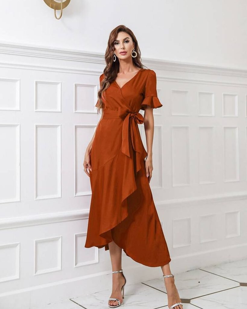woman wearing a rust orange ruffled wrap dress with a waist tie and heels