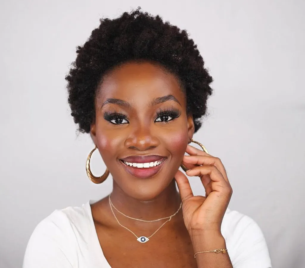smiling woman with short cropped natural kinky afro hair wearing gold hoop earrings