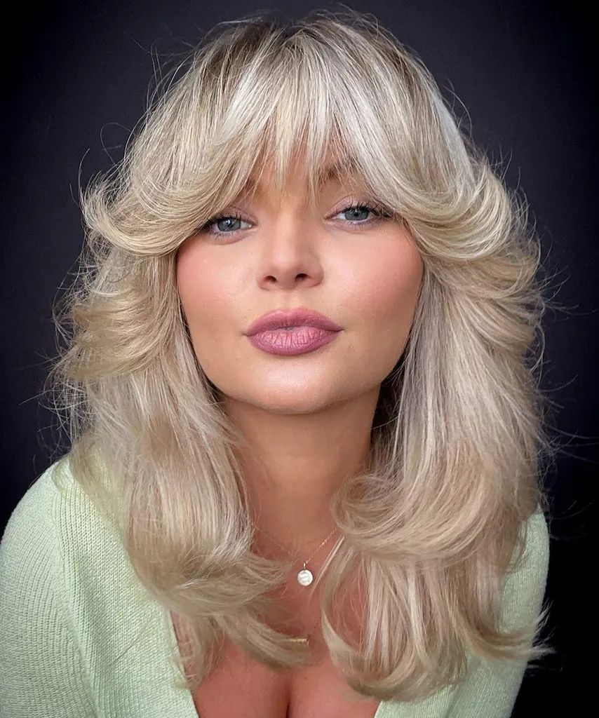 woman with voluminous layered blonde hair and feathered face-framing curtain bangs