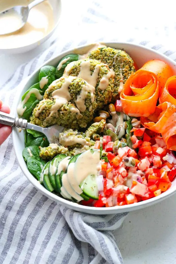 baked falafel bowl with cucumbers, carrots, and tomatoes drizzled with tahini dressing
