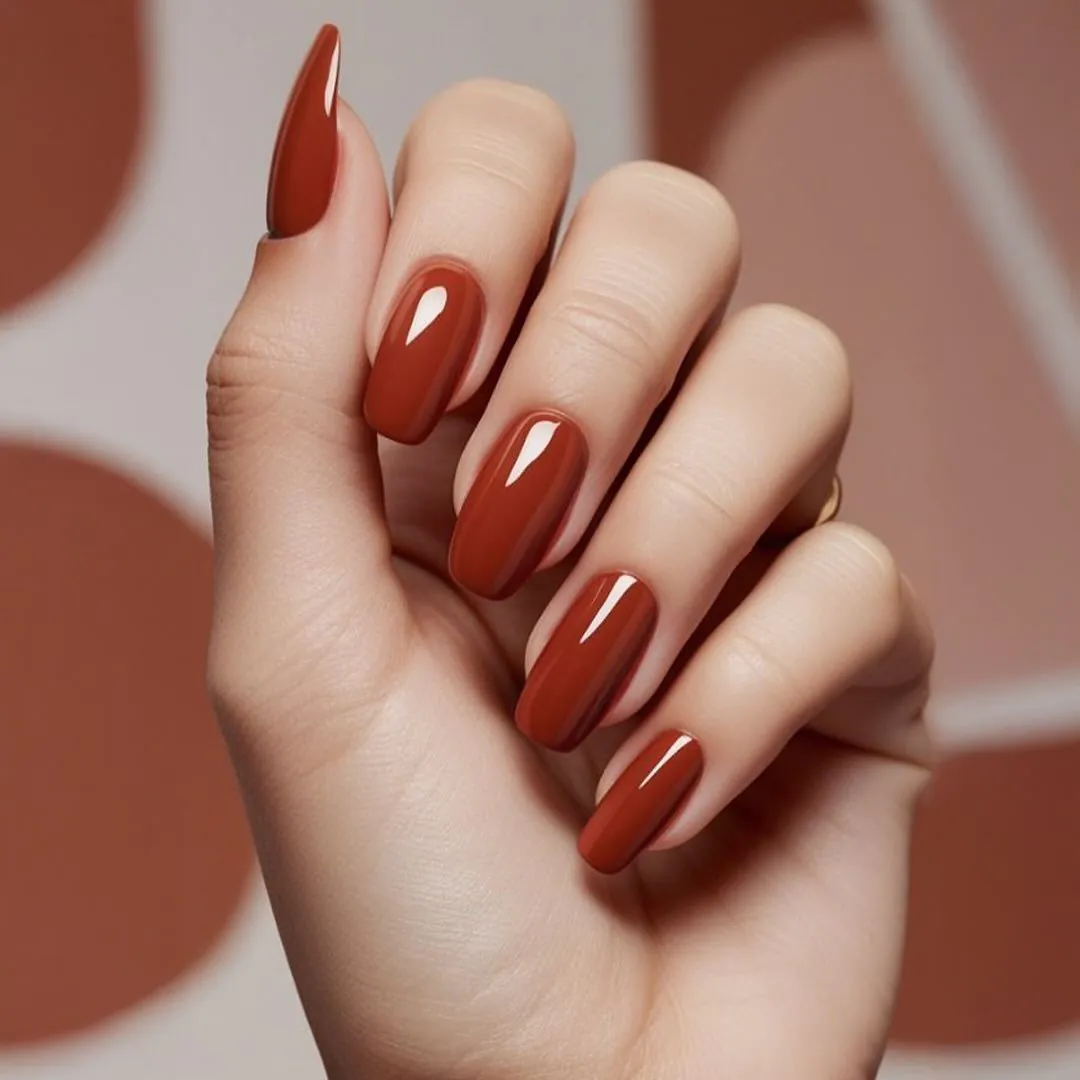 glossy terracotta brown manicure on a hand with an abstract background