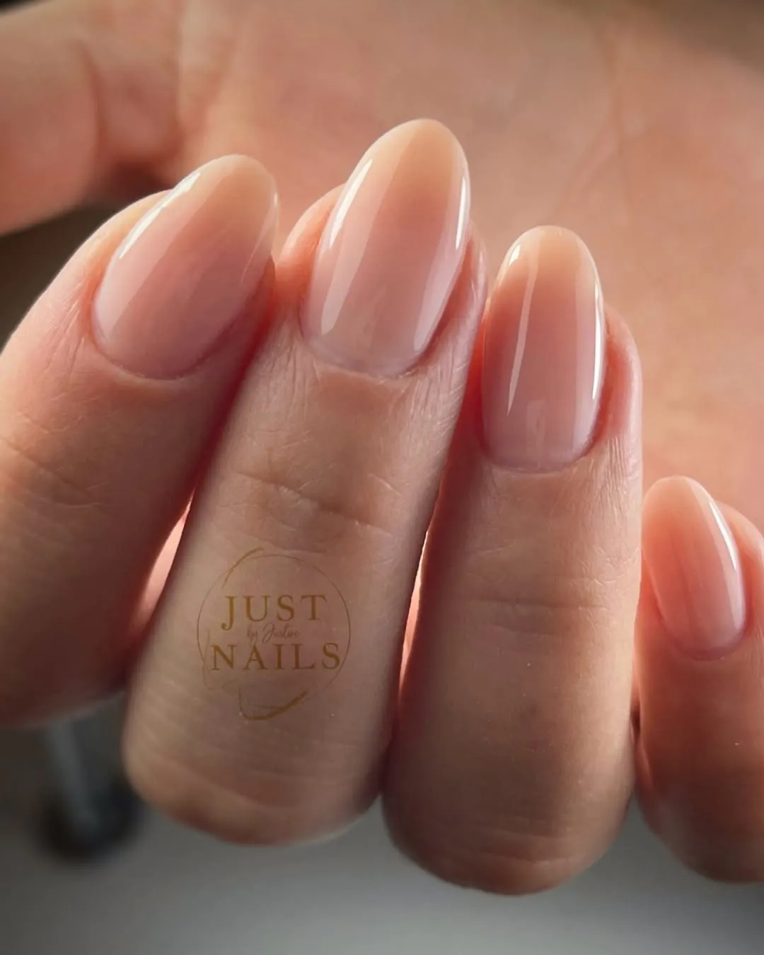 closeup of a glossy nude gel manicure on long oval shaped nails