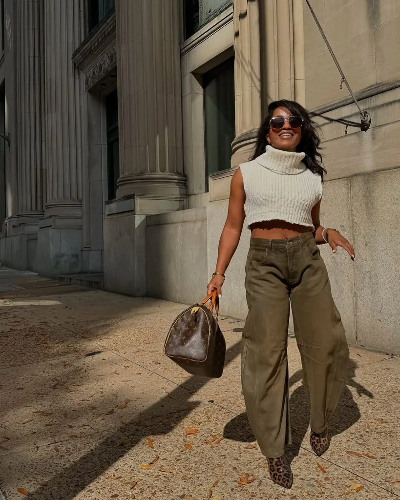 woman in cropped cream sweater and olive green wide leg pants walking outside