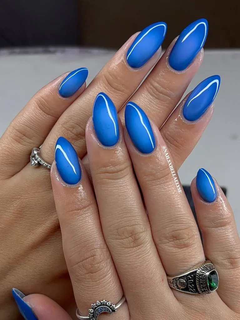 glossy vibrant royal blue almond shaped nails on hands with rings