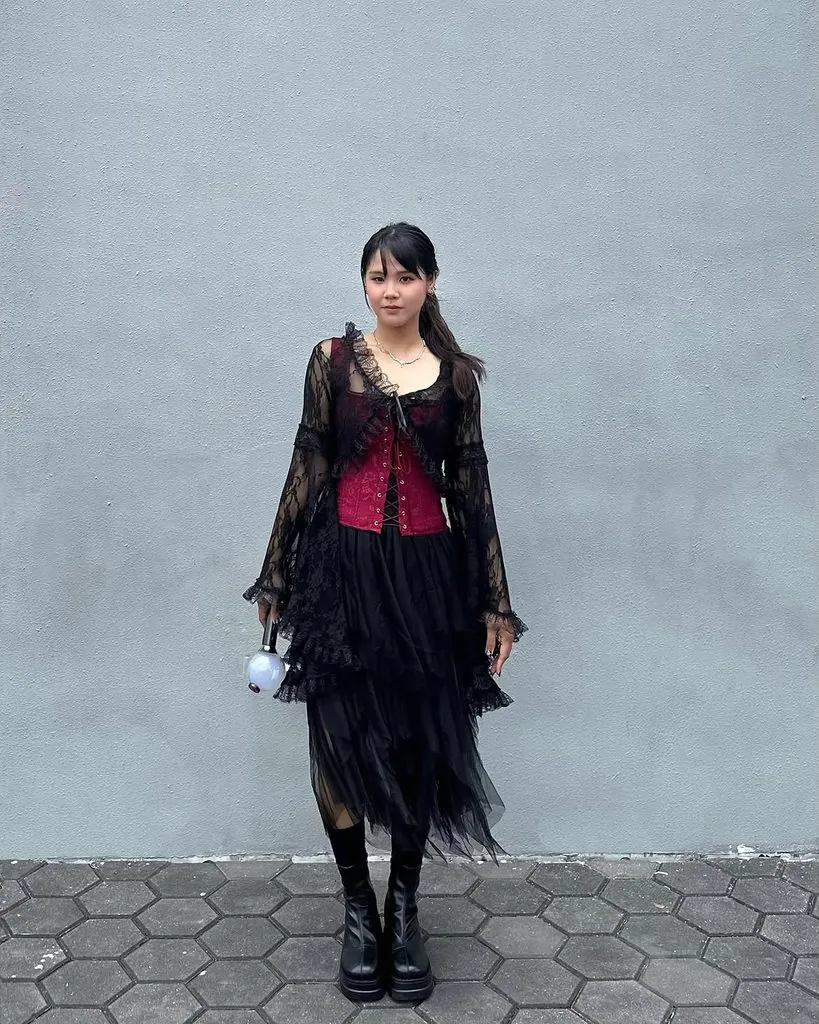 woman in red corset, black lace cardigan, and black tulle skirt