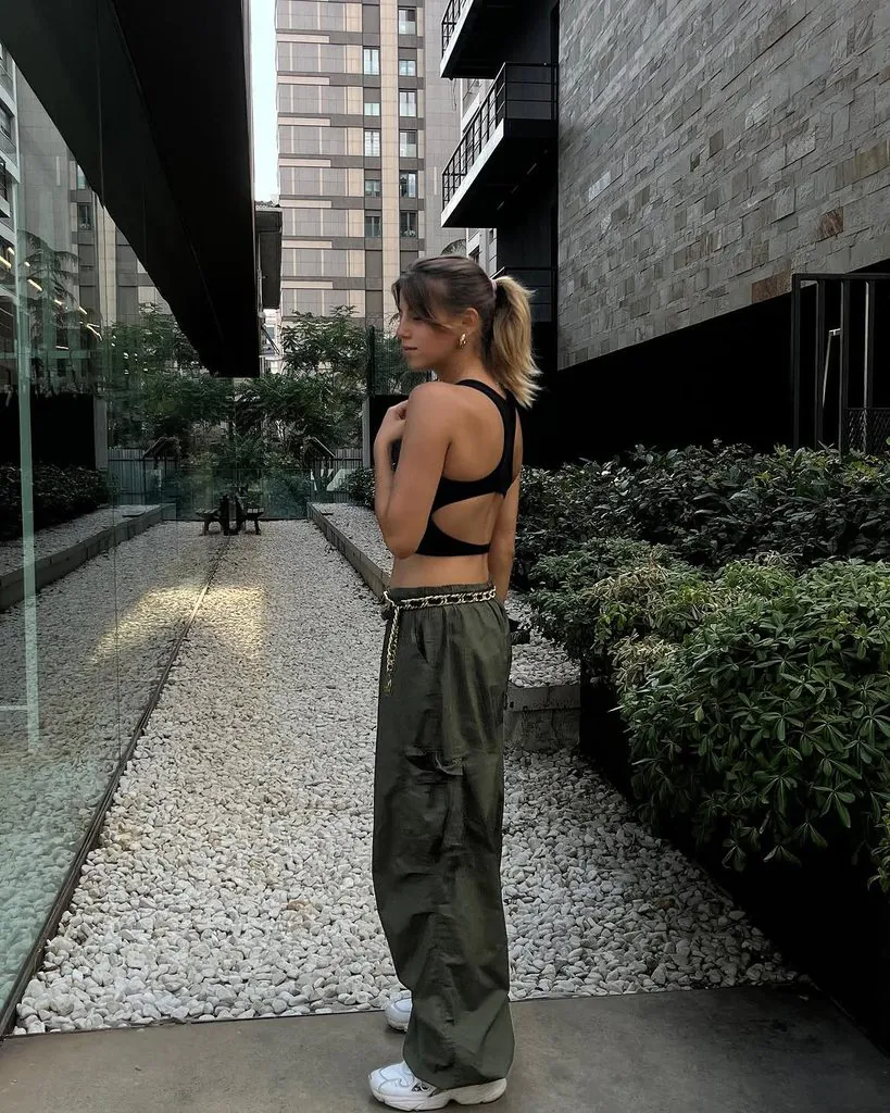 woman in black cutout crop top, olive green cargo pants, and sneakers