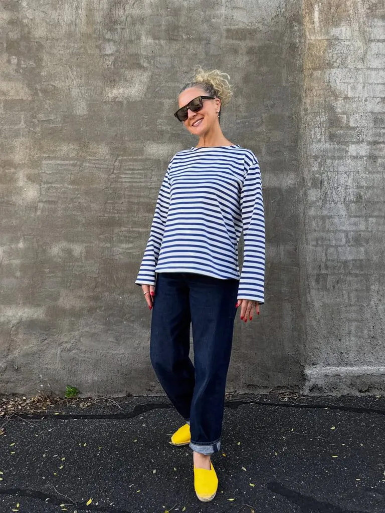 woman wearing a striped long sleeve shirt, dark cuffed jeans, and bright yellow shoes