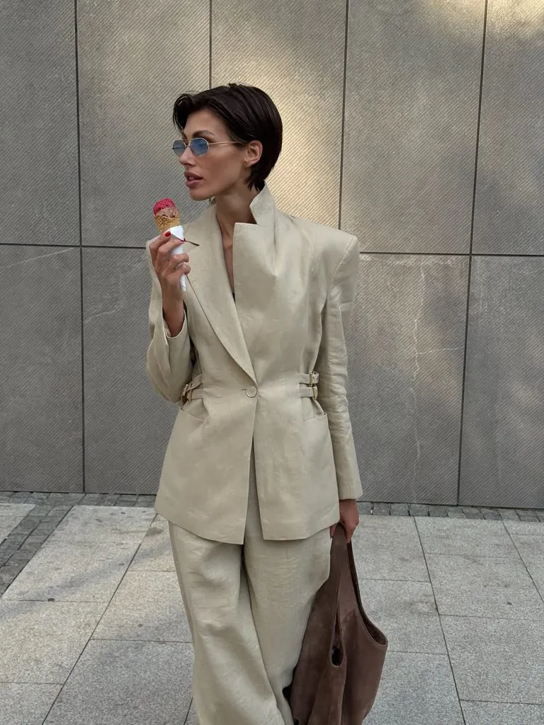 woman wearing beige linen blazer suit holding brown bag while eating ice cream cone