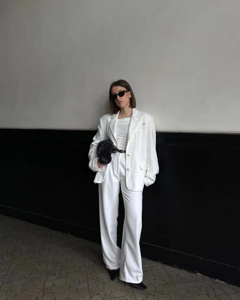 woman wearing white linen blazer and matching white wide leg pants against a wall