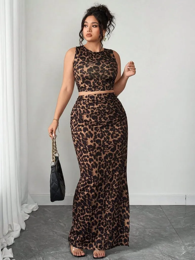 woman wearing a matching leopard print sleeveless crop top and ruched maxi skirt holding a bag