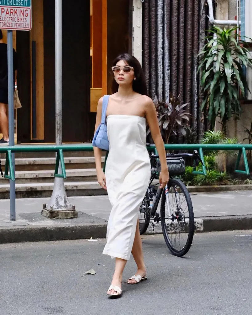 woman walking in strapless white midi dress carrying a blue shoulder bag