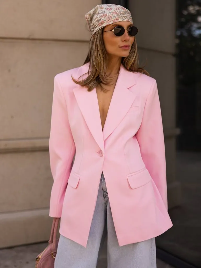 woman in pink oversized blazer sunglasses and patterned headscarf posing outdoors