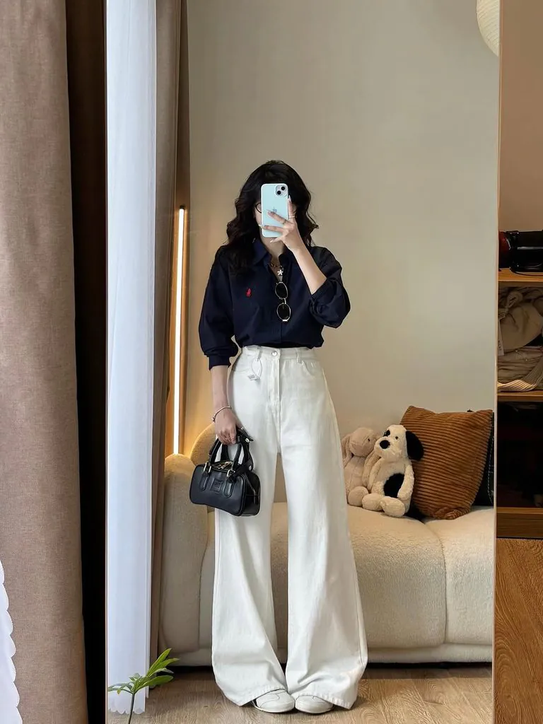 woman in navy button down shirt and white wide leg trousers mirror selfie