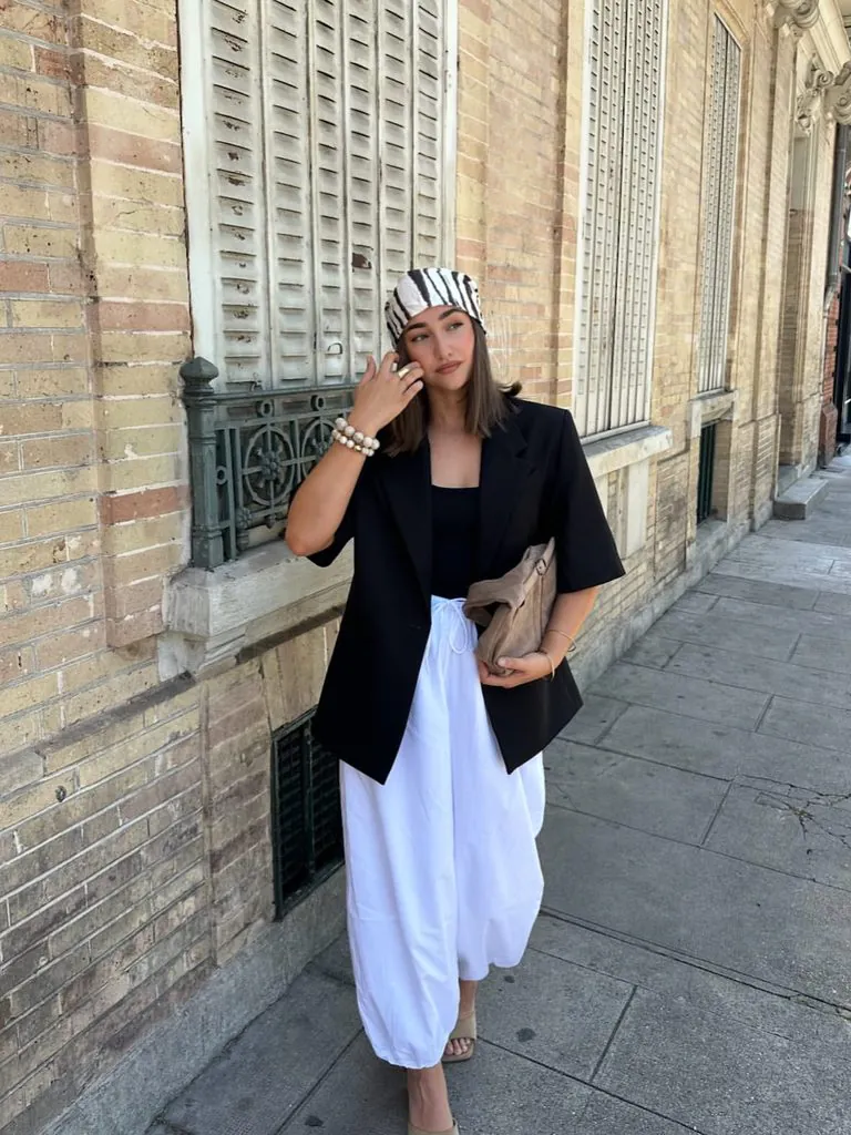 woman wearing black blazer white wide leg trousers and zebra print headscarf
