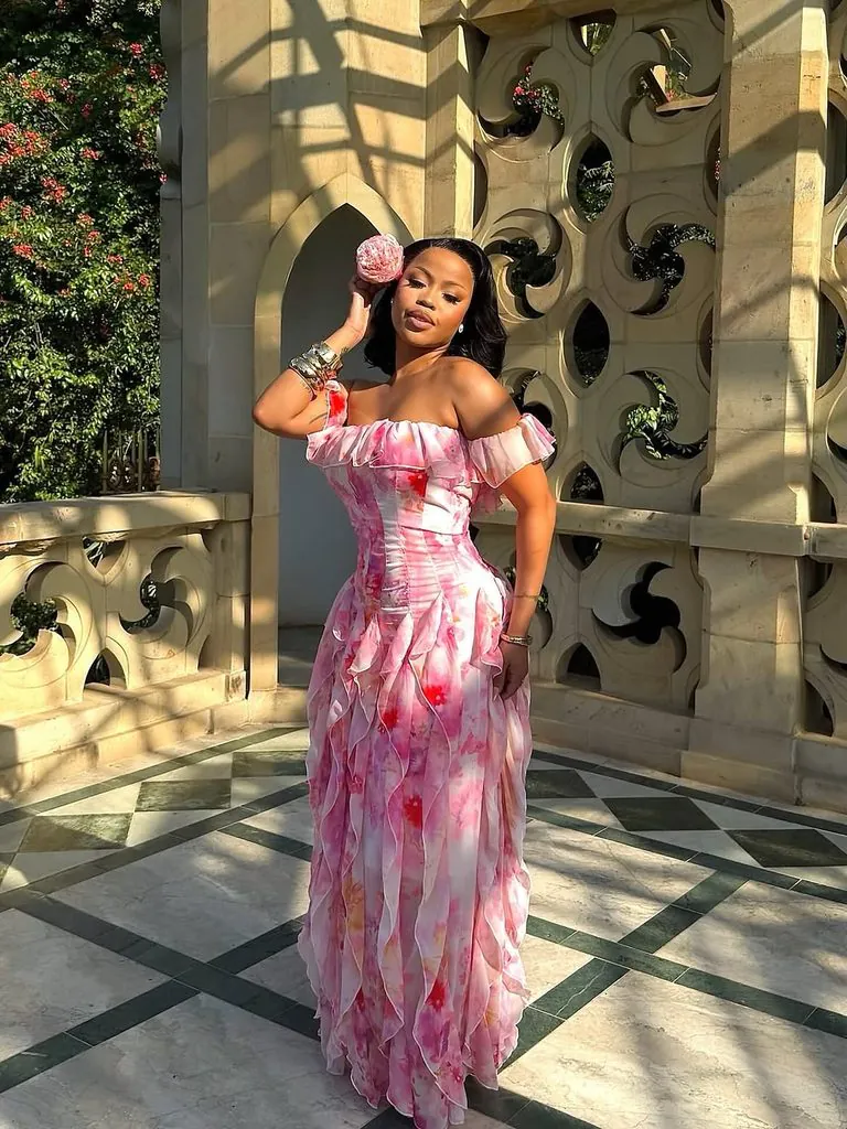 woman wearing elegant pink floral ruffled maxi dress posing by stone columns