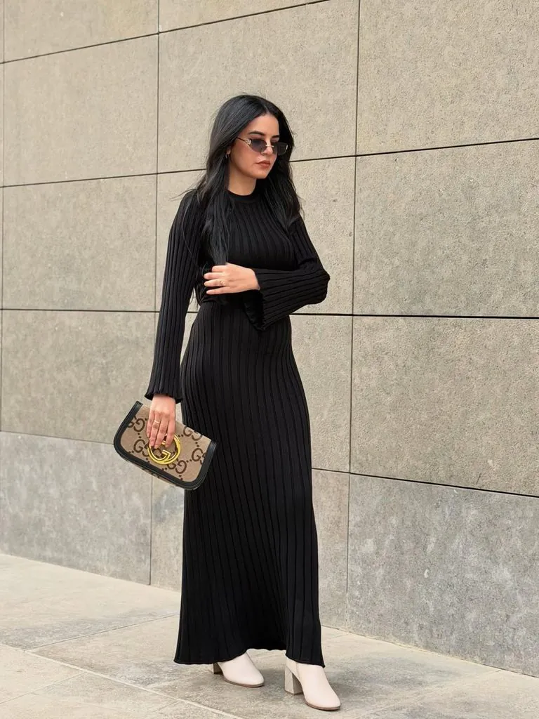 woman in black ribbed long sleeve maxi dress holding printed clutch